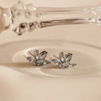 Aquamarine Marquise Studs featuring silver floral design and marquise-cut gemstones, perfect as a bridesmaids gift, shown on cream fabric next to a glass accessory.