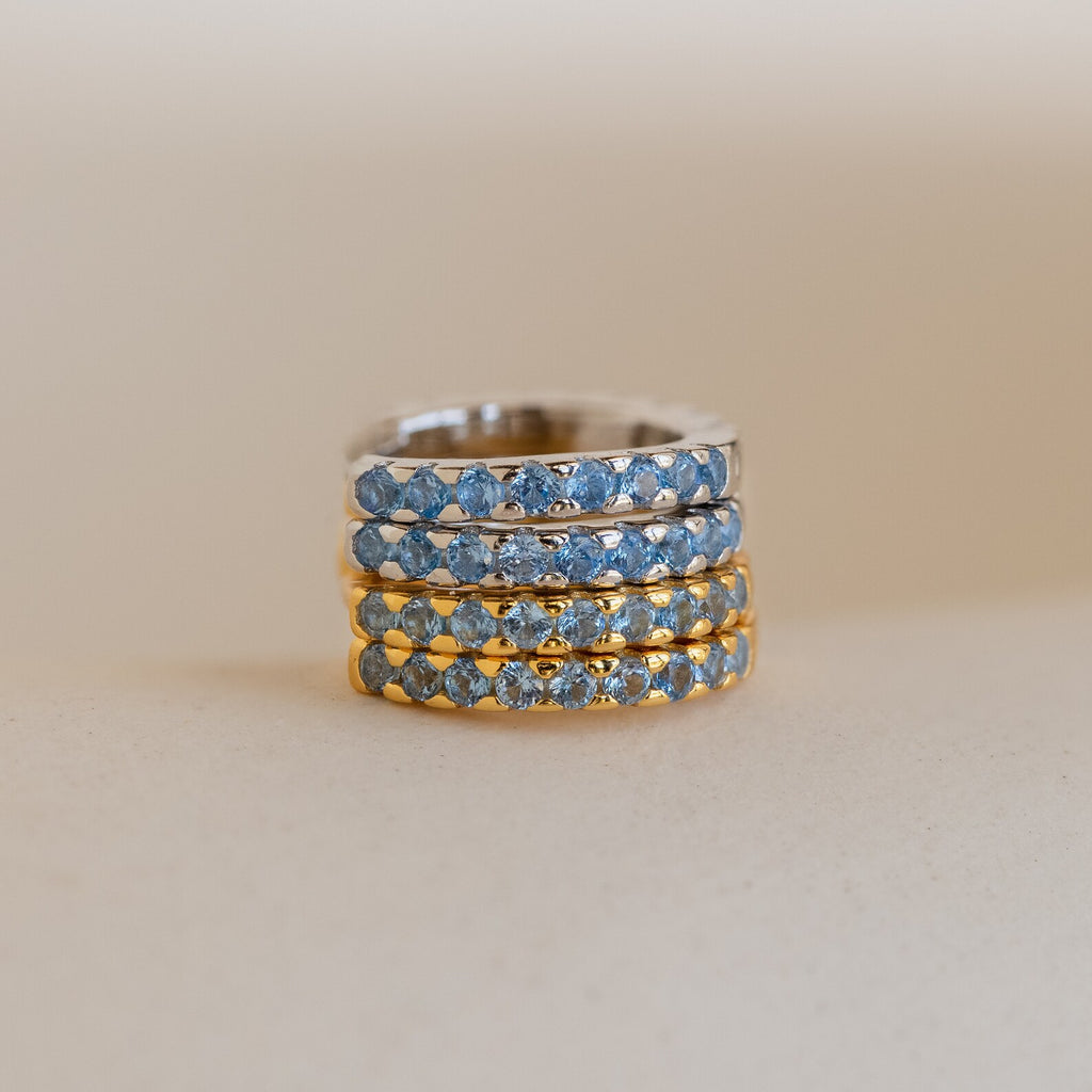Four Aquamarine Pave Huggies are stacked on a neutral background, their sparkling gemstones reminiscent of an elegant earring stack or the shimmer of blue diamond hoop earrings.