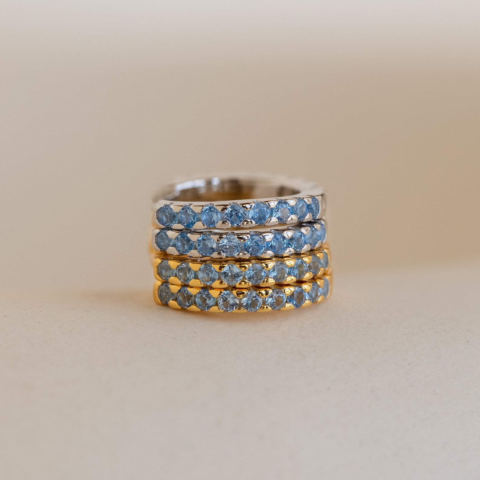 Four Aquamarine Pave Huggies are stacked on a neutral background, their sparkling gemstones reminiscent of an elegant earring stack or the shimmer of blue diamond hoop earrings.