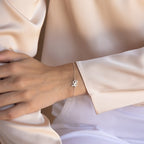 Model wearing the Carrie Initial Bracelet with a cursive “L” charm, paired with light, silky clothing—a stunning showcase of personalized jewelry.