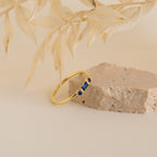 The Morse Code Birthstone Ring features a blue gemstone set in gold, combining personalized style and timeless charm—ideal for anyone seeking unique jewelry with a meaningful touch.