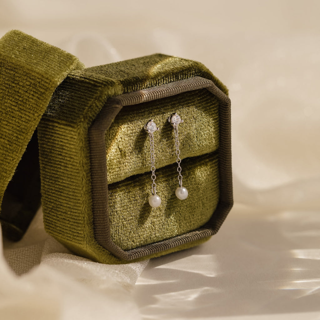 A green box with Diamond Pearl Drop Earrings inside.