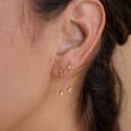 Close-up of an ear wearing Mixed Crystal Drop Earrings: gold minimalist style with pink star-shaped stones, small clear gems, and delicate dangling chains.