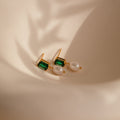 Emerald Pearl Drop Earrings, featuring vintage green gemstones and delicate white pearls, displayed on a soft beige background with gentle shadows.