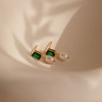 Emerald Pearl Drop Earrings, featuring vintage green gemstones and delicate white pearls, displayed on a soft beige background with gentle shadows.