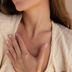 Woman with light brown hair wears a cream textured top and the Dainty Aventurine Bar Necklace, gently resting her hand on her chest.