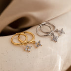 Two pairs of Diamond Flower Huggies—one in gold, one in silver—displayed on a soft neutral surface