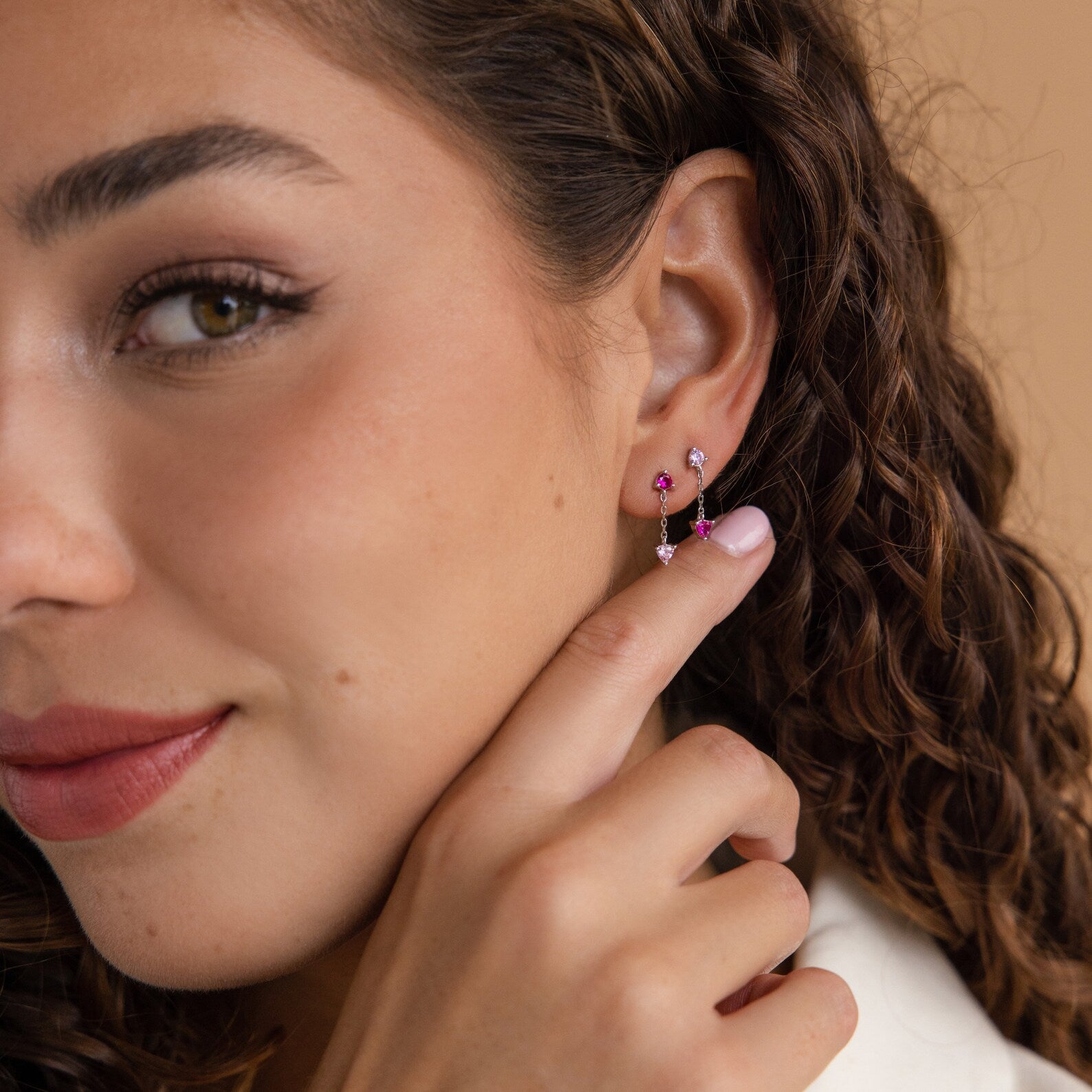 A woman with curly hair wears Mixed Pink Drop Earrings.