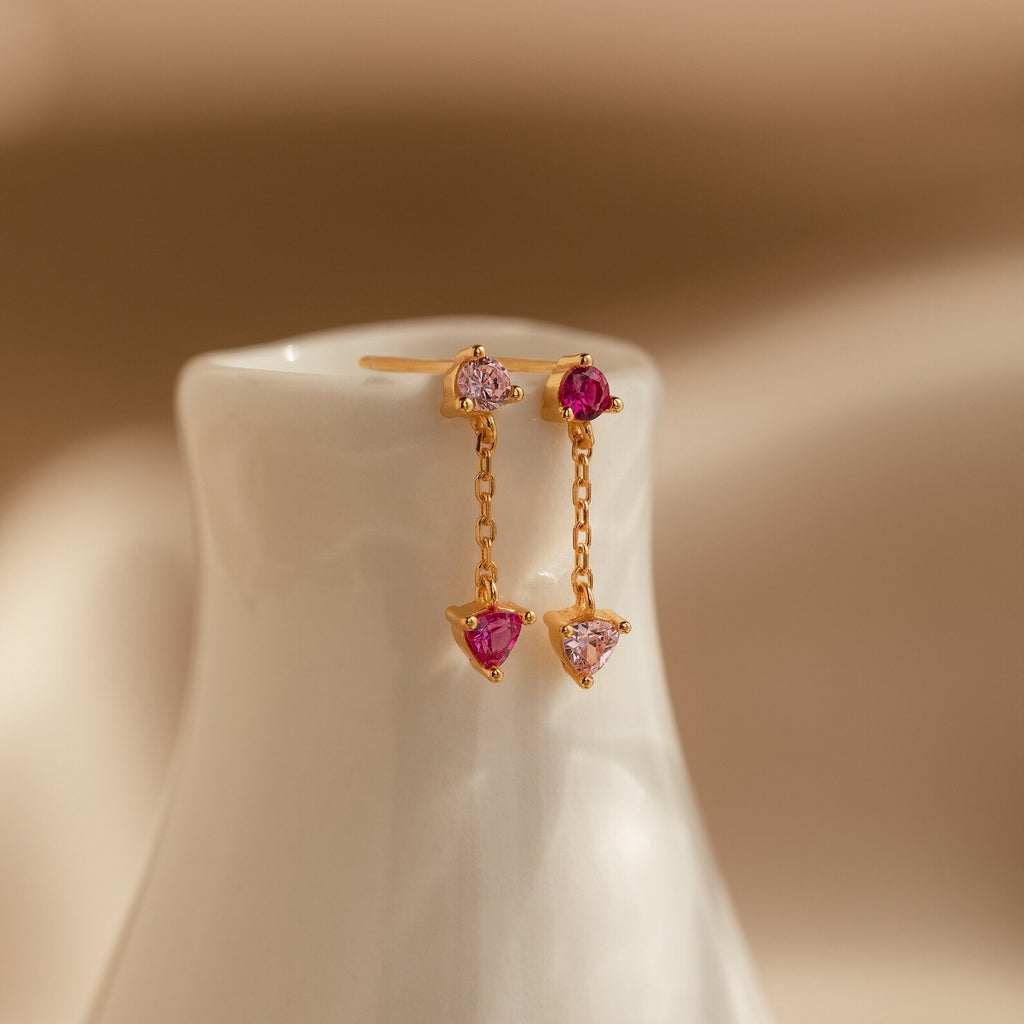Mixed Pink Drop Earrings featuring pink and clear gemstones, shown on a glossy white ceramic stand.