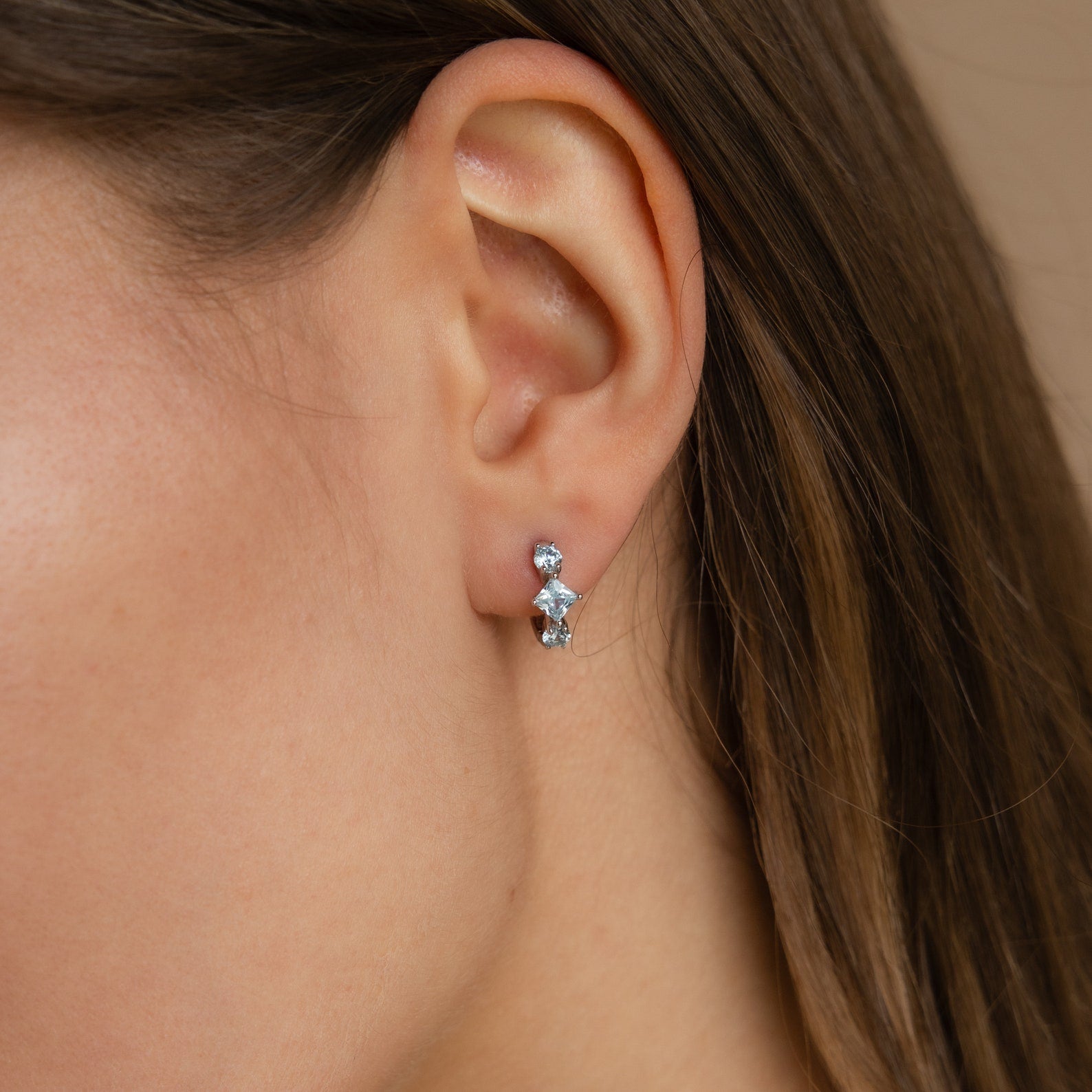 Model wearing the silver Aquamarine Diamond Huggies styled on the ear, showcasing all three aquamarine stones.