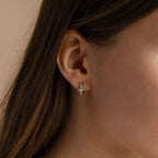 Close-up of a model wearing the gold Aquamarine Diamond Huggies on her ear, with two stones vertically aligned.