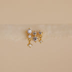 The Triple Diamond Studs Set features gold stacking earrings, each with three clear gemstones reminiscent of diamond drops, showcased on a soft neutral background.