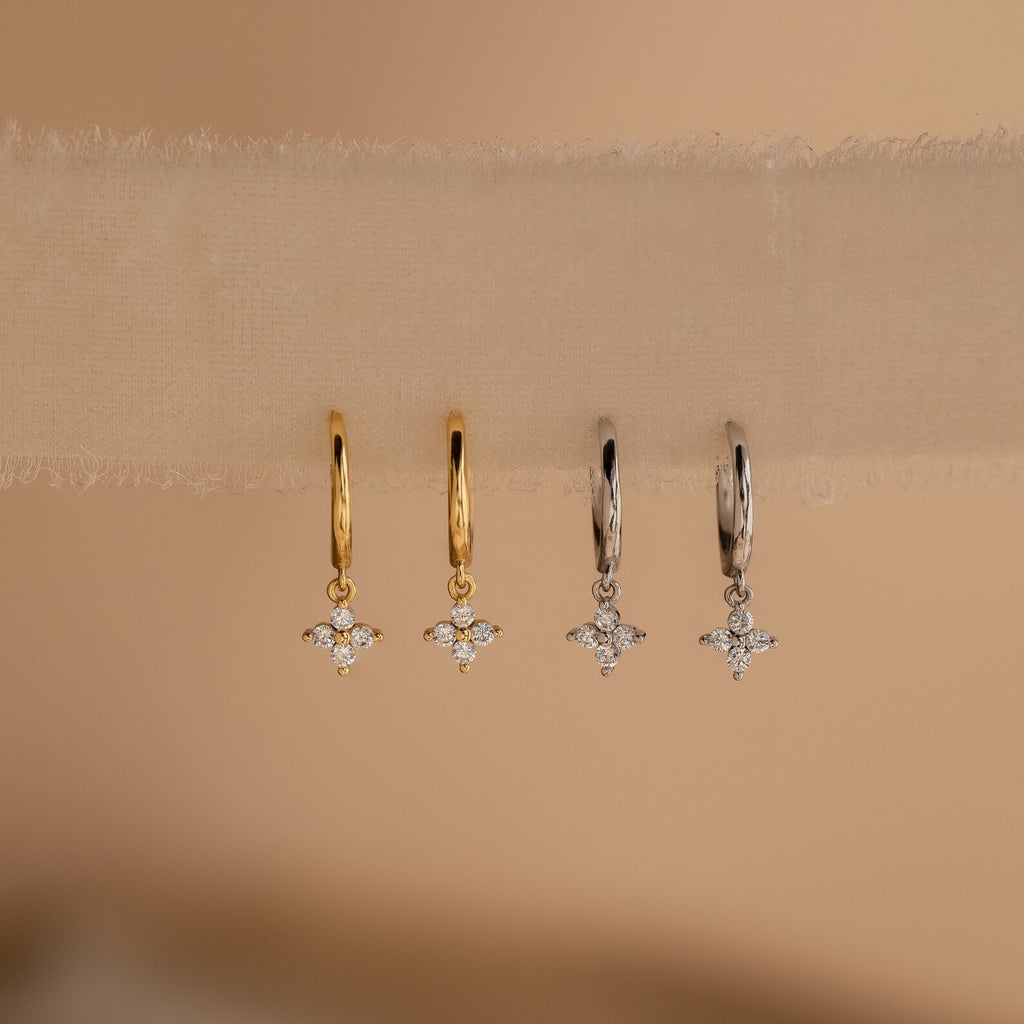 Four Diamond Flower Huggie earrings (two gold, two silver) neatly aligned on a soft tulle ribbon
