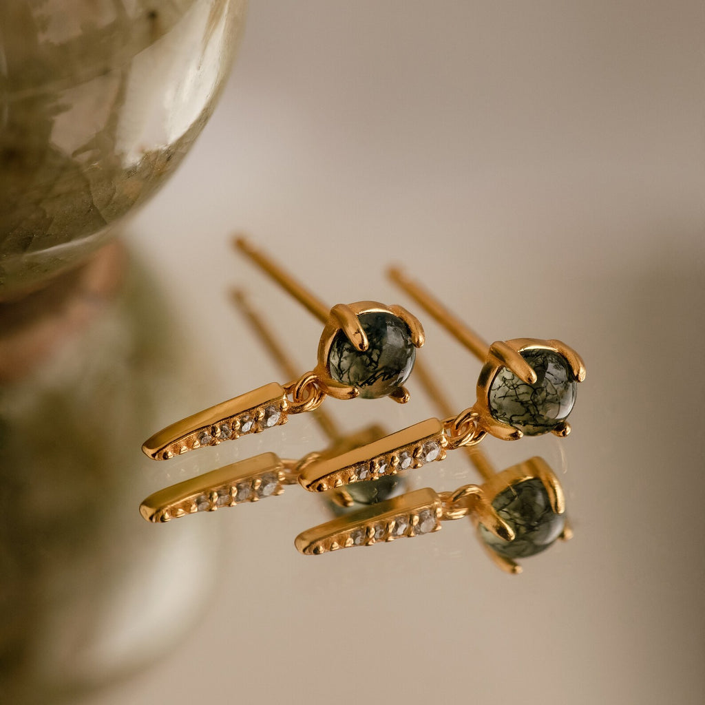 A collection of elegant jewelry, featuring gold dagger-shaped earrings and Agate Diamond Drop Earrings embellished with vibrant gemstones.