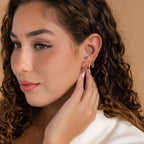 Woman with curly hair wears Vera Pave Birthstone Huggies, gently touching her ear and looking to the side.