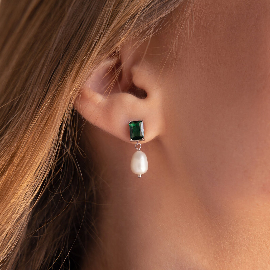 Close-up of an ear adorned with Emerald Pearl Drop Earrings, featuring vintage-inspired emerald green and pearl drops.