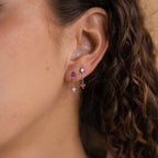 Close-up of a woman's ear with curly brown hair, wearing Mixed Pink Drop Earrings—romantic mismatched earrings featuring dazzling pink gemstones.