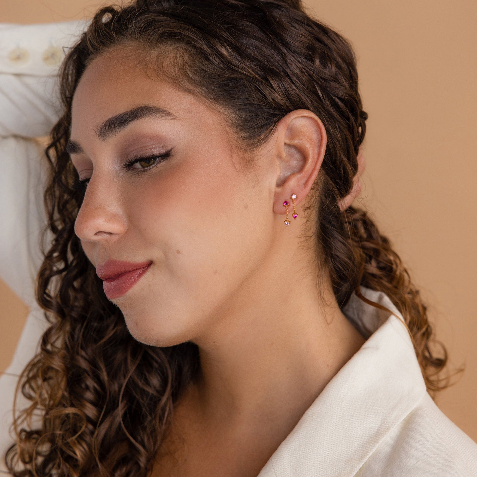 A woman with curly hair wears Mixed Pink Drop Earrings and a white top, posing against a beige background.