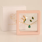 Gold and green gemstone necklace and earring set in a pink display case with a Caitlyn Minimalist box—perfect as a Birthstone Mystery Box or for a personalized surprise gift.