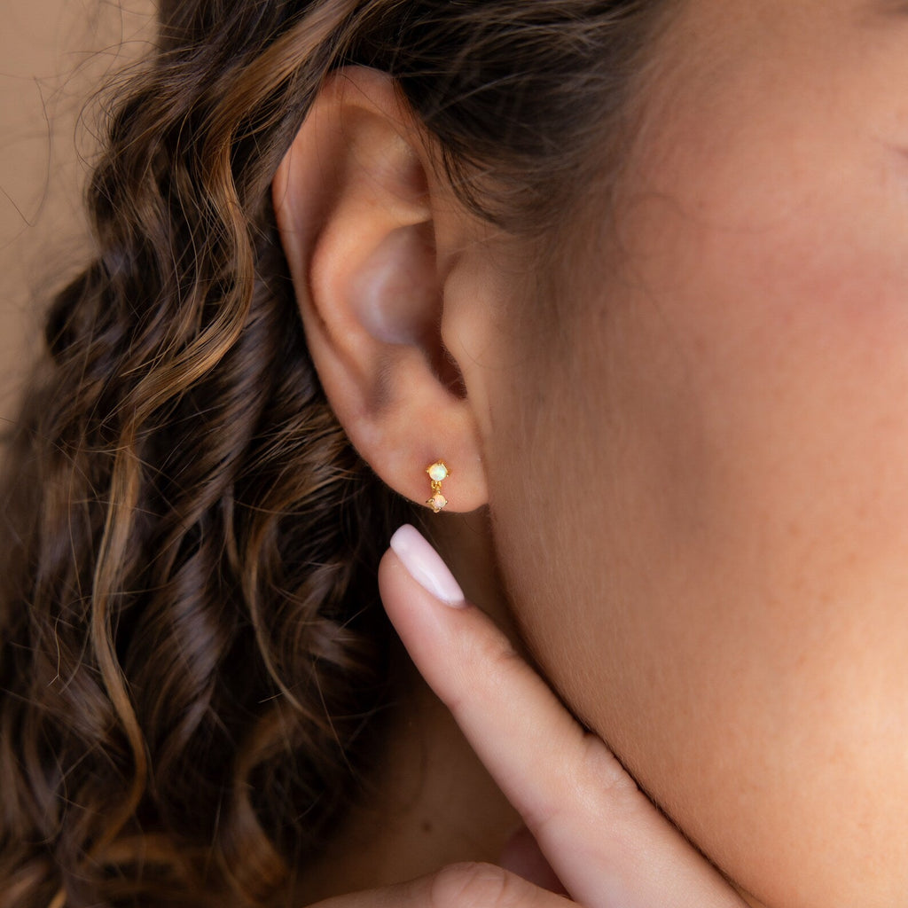 A close-up of a woman’s ear adorned with Ruby Birthstone Drop Studs.