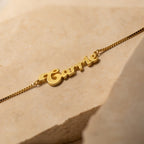 Groovy Name Necklace in Box Chain displayed on a neutral stone background—a stylish, customizable piece of jewelry with your chosen name in a trendy script.