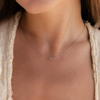 A close-up of a woman's neck wearing the Dainty Aventurine Bar Necklace, a delicate silver chain featuring a small green crystal bar pendant.