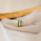 A pair of Green Opal Inlay Hoops featuring vibrant green stones, displayed on a white cloth.
