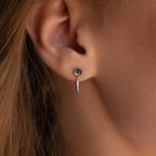 Close-up of a woman's ear adorned with Agate Diamond Drop Earrings—a small stud paired with a dangling dagger-shaped charm, exuding elegance.