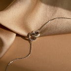 Interlocking Opal Inlay Necklace and Bracelet Set in Silver, inspired by interlocking rings, displayed on beige satin fabric under soft, warm lighting.