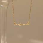 A Dainty Bubble Name Necklace featuring the word "mama" in gold bubble letters hangs against a neutral background, highlighting elegant personalized jewelry.