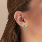 Close-up of a woman's ear wearing Green Opal Inlay Huggies, with brown hair tucked behind her ear.