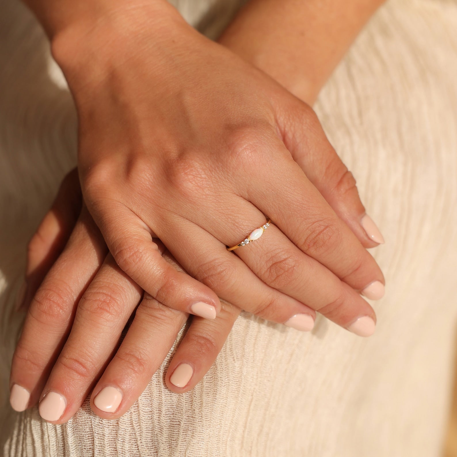 Close-up of hands with pale nude nail polish, adorned with the Marquise Opal Diamond Ring for a subtle touch of elegance.