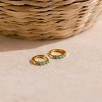 Garden Green Opal Huggies rest on a beige surface, ideal for stacking. A woven basket adds a natural touch in the background.