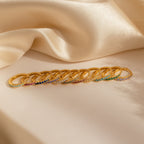 A row of Vera Ruby Birthstone Huggies with vibrant gemstones displayed on cream-colored satin fabric.