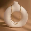 Diamond Paperclip Necklace with minimalist gold oval links draped over a round white ceramic vase on a beige background.