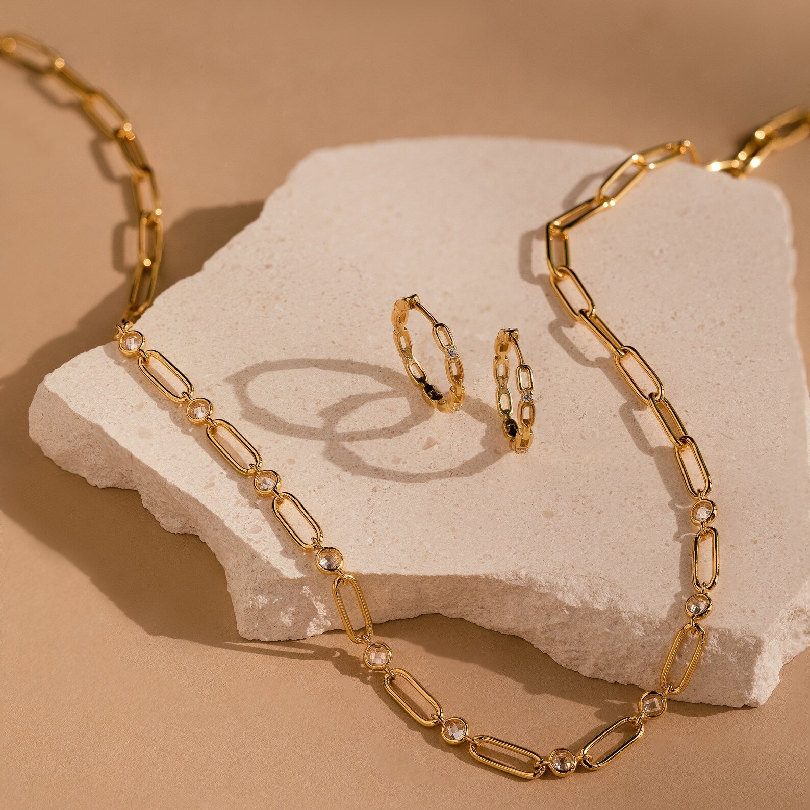 Diamond Link Hoops displayed on a light stone against a beige background.