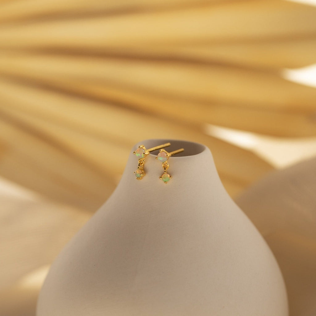 Opal Birthstone Drop Studs displayed on a smooth, light beige vase with a soft, neutral background—perfect as elegant birth month jewelry or dainty earrings for any occasion.