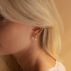 Close-up of a blonde woman wearing three gold earrings, including the Dainty Opal Teardrop Studs, for an elegant touch.