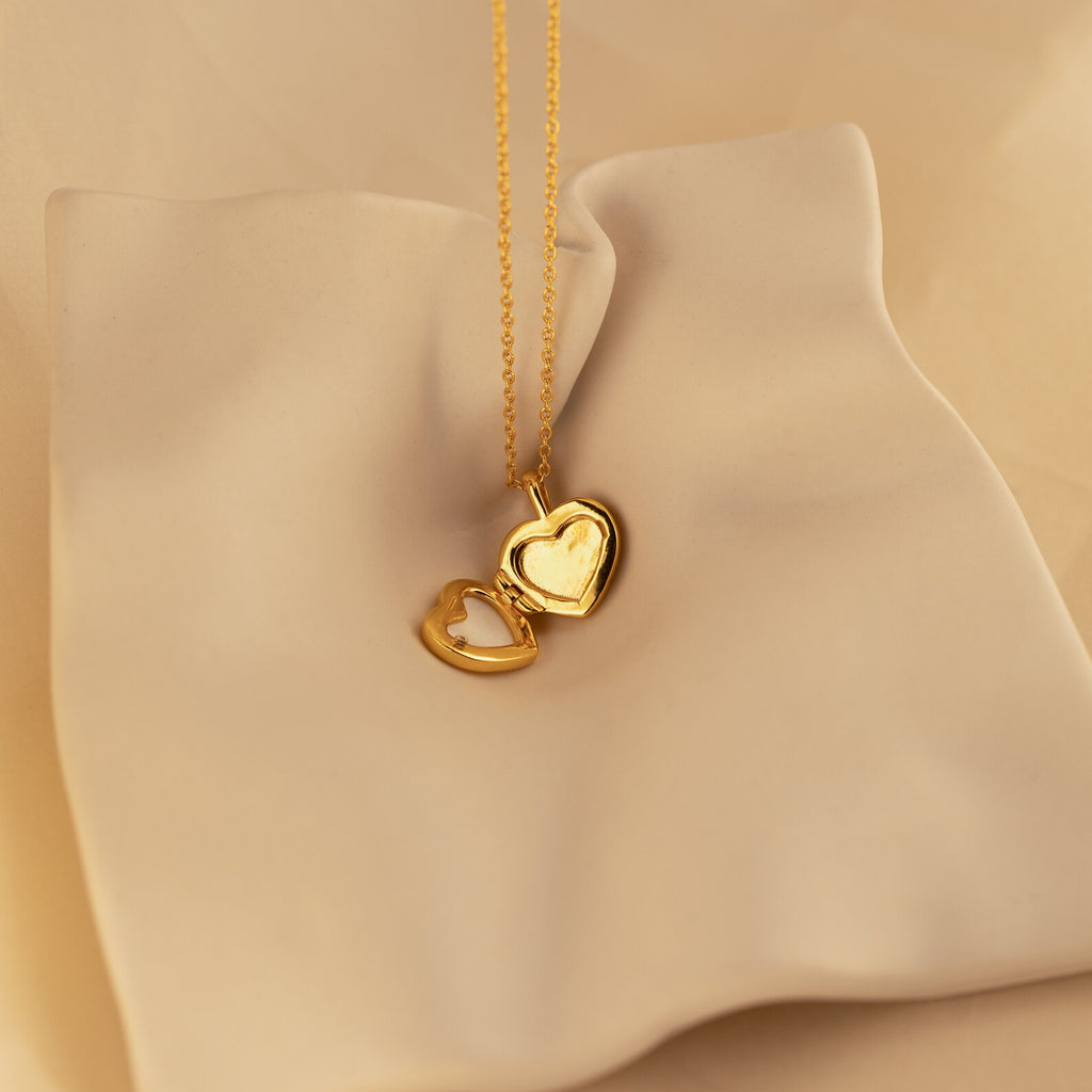 Pearl Heart Locket Necklace showcased on a smooth, cream-colored fabric—nostalgic and timeless jewelry ideal for any occasion.
