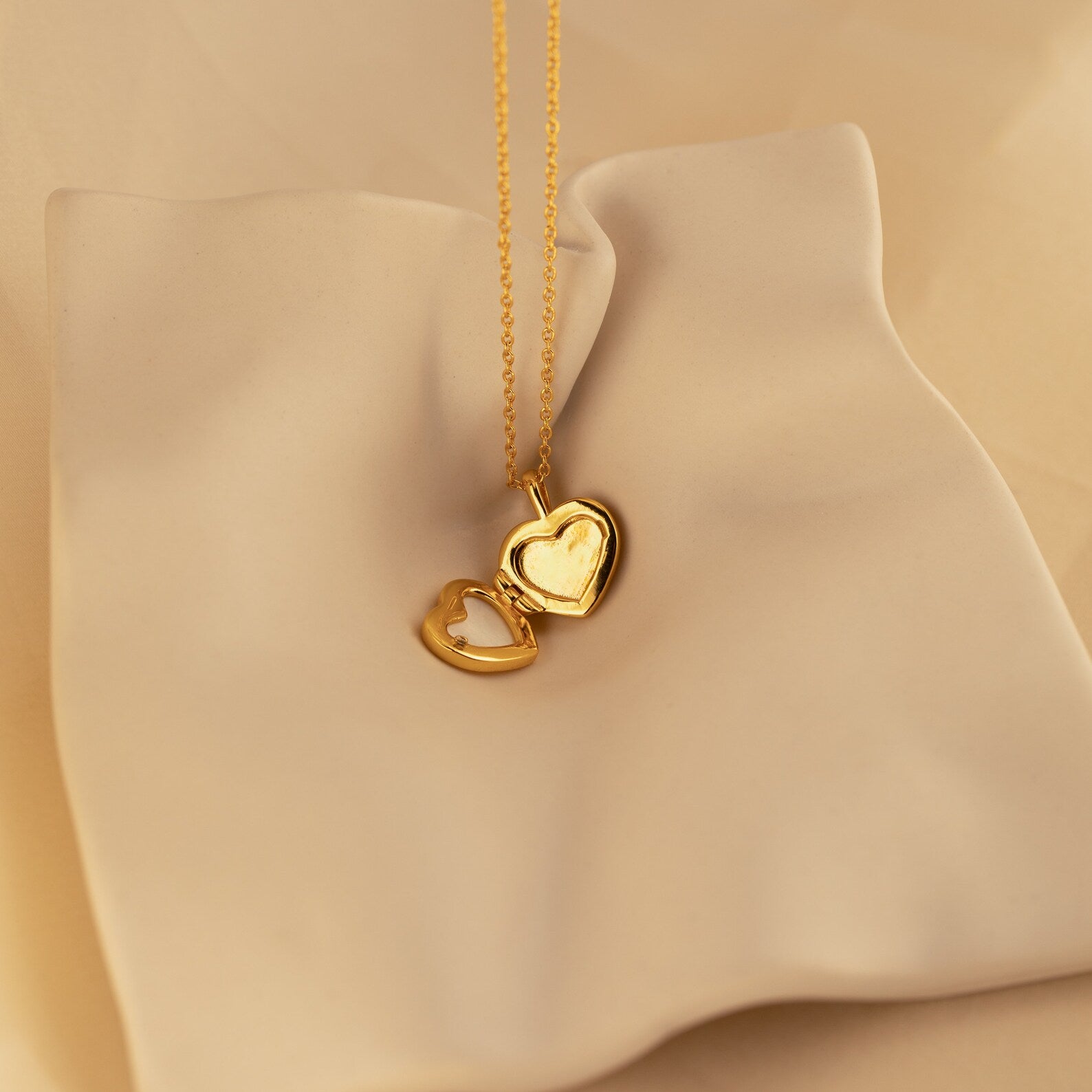 Pearl Heart Locket Necklace showcased on a smooth, cream-colored fabric—nostalgic and timeless jewelry ideal for any occasion.