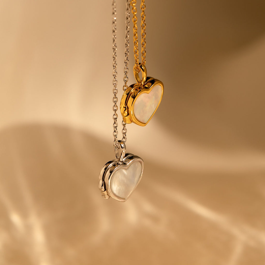 Two heart-shaped pendants—one gold, one silver—feature a white center inspired by the Pearl Heart Locket Necklace, making these nostalgic pieces a lovely addition to any jewelry collection.