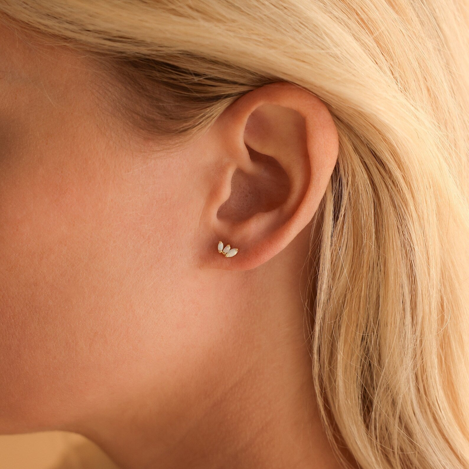 Close-up of a woman's ear wearing Opal Marquise Studs—small, gold, leaf-shaped earrings that make an elegant addition to any floral jewelry collection.