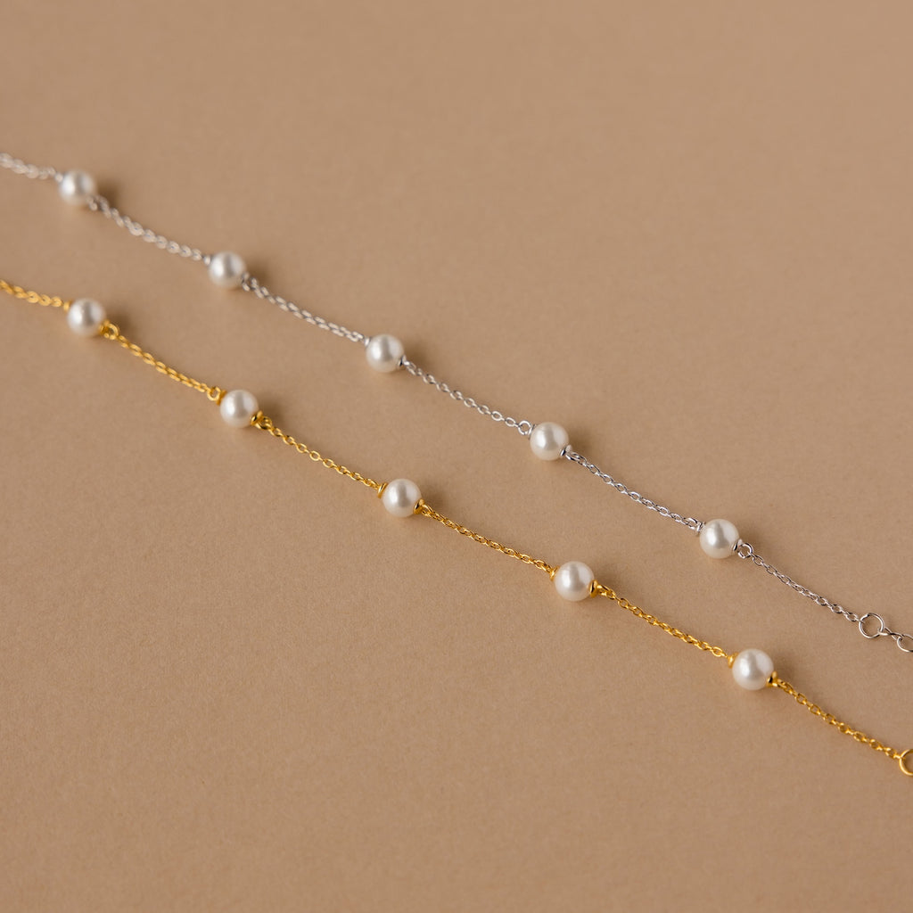 The Pearl Station Bracelet set features two delicate chain bracelets—one silver, one gold—each with evenly spaced white pearls, making it the perfect modern accessory to add elegance to any look.