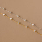 The Pearl Station Bracelet set features two delicate chain bracelets—one silver, one gold—each with evenly spaced white pearls, making it the perfect modern accessory to add elegance to any look.