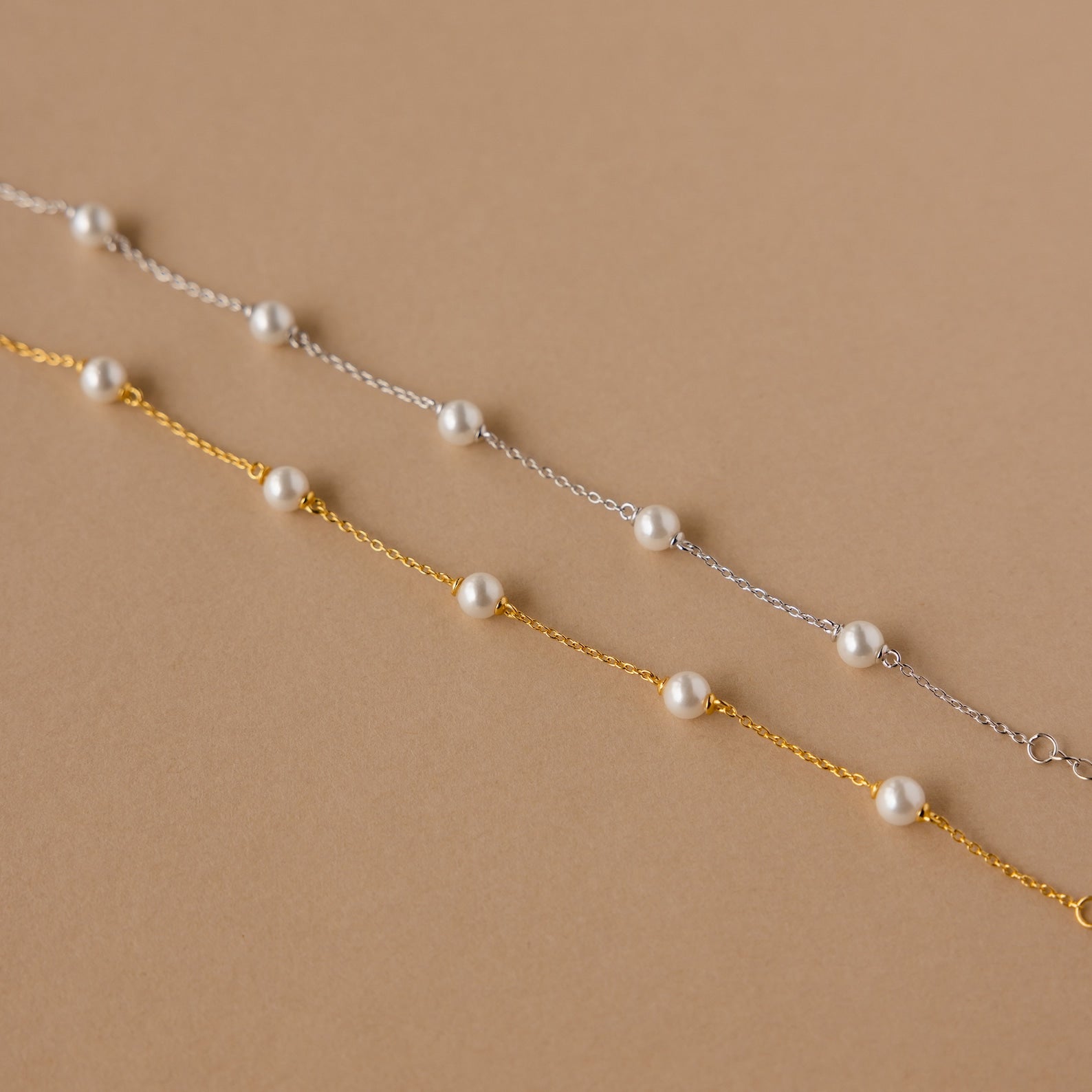 The Pearl Station Bracelet set features two delicate chain bracelets—one silver, one gold—each with evenly spaced white pearls, making it the perfect modern accessory to add elegance to any look.