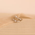 Silver pearl diamond huggie earrings laid on textured ivory fabric, highlighting their refined detail.