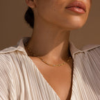A woman shown from the shoulders up wears a cream pleated blouse and the Diamond Paperclip Necklace.