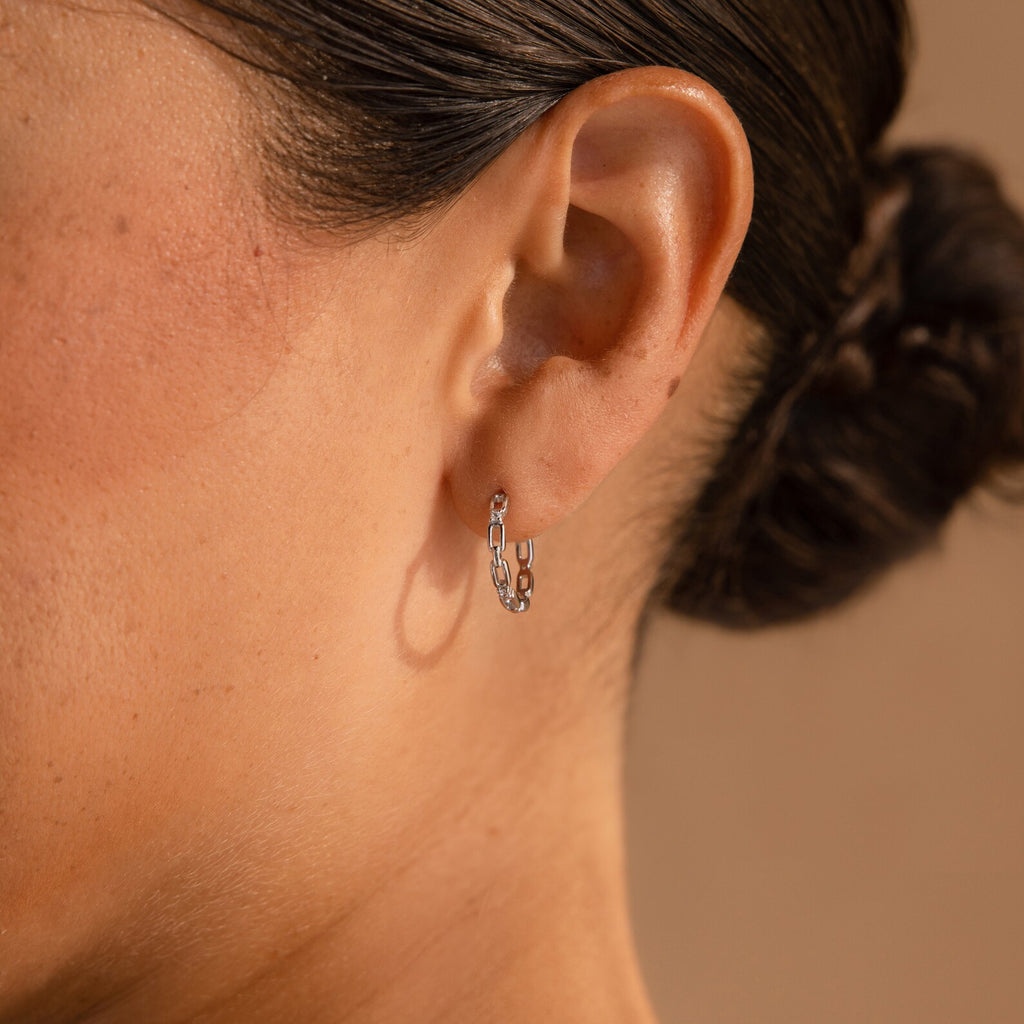 Close-up of a woman's ear wearing Diamond Link Hoops—small silver chain link earrings with diamonds, ideal as delicate bridal jewelry.