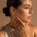 Woman with smooth skin touches her neck while wearing Diamond Link Hoops and gold rings, set against a neutral background.