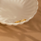 The Dainty Mama Ring sits inside a white, scalloped ceramic dish on a beige surface—a charming and thoughtful gift for moms.